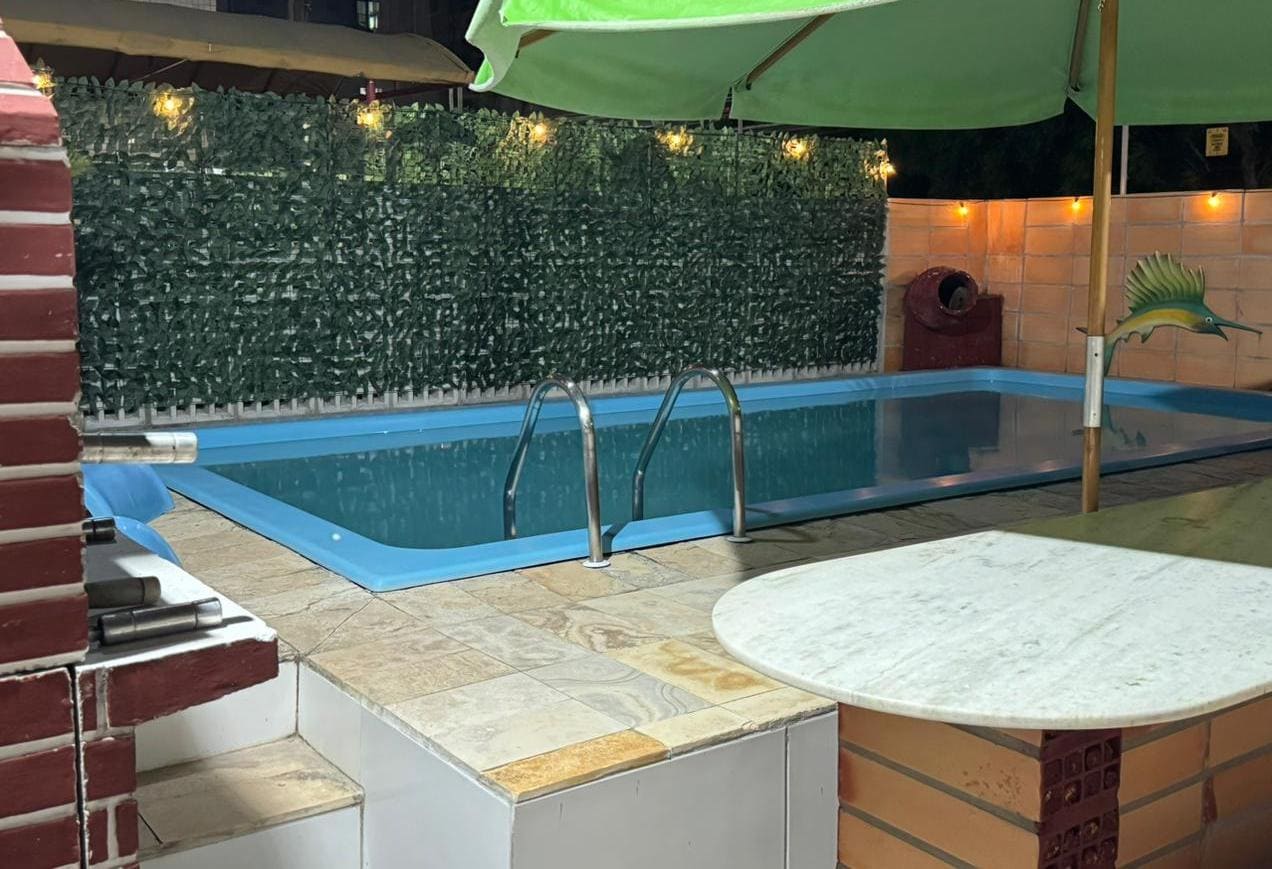 Piscina iluminada à noite na Vila Flat Bessa